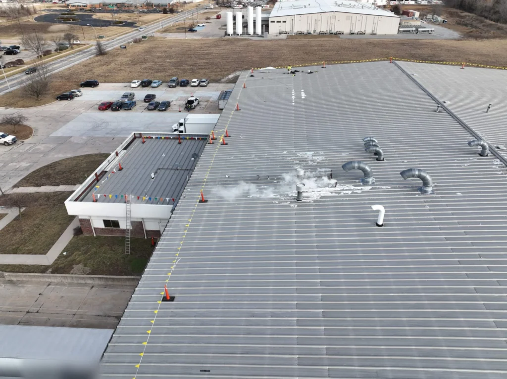 Rooftop exhaust vents releasing steam on an existing metal roof at an operating laundry facility