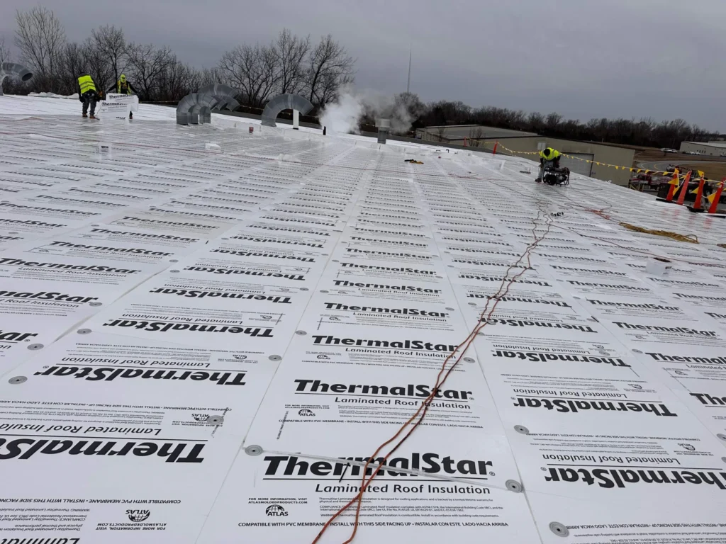 Crew installing ThermalStar coverboard over the insulated flutes of a metal roof